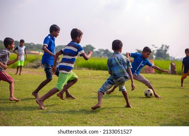 Gowainghat, Bangladesh – November 06, 2019: Children Playing Football On The Field. School Going Kids Playing Soccer Game To Win School League. Boy Defending Football From The Attack For A Goal.