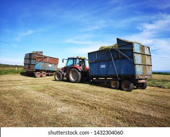 Gower, UK: June 23, 2019: A Farm Worker Is Driving A Tractor In The Fields In Rural Wales. Sunny, Blue Sky Background. Summer Harvesting Concept. 