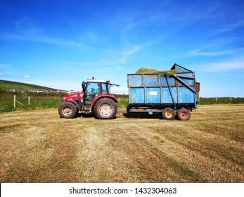 Gower, UK: June 23, 2019: A Farm Worker Is Driving A Tractor In The Fields In Rural Wales. Sunny, Blue Sky Background. Summer Harvesting Concept. 