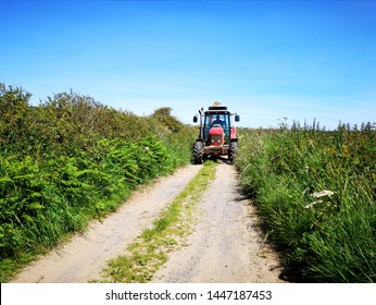 Gower, UK: June 23, 2019: A Farm Worker Is Driving A Tractor In The Lanes Around The Fields. 