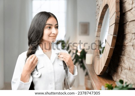 GP doctor is getting ready for work and looking at herself in the mirror 