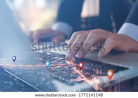 GPS map, pin address location on mobile apps. Double exposure of man hand using laptop computer searching target place on night cityscape. Business and technology, marketing plan concept