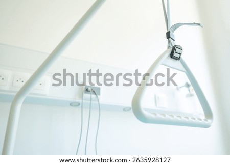 A grab bar hangs from a support structure in a well-lit medical facility room designed for patient assistance and safety during physical rehabilitation.