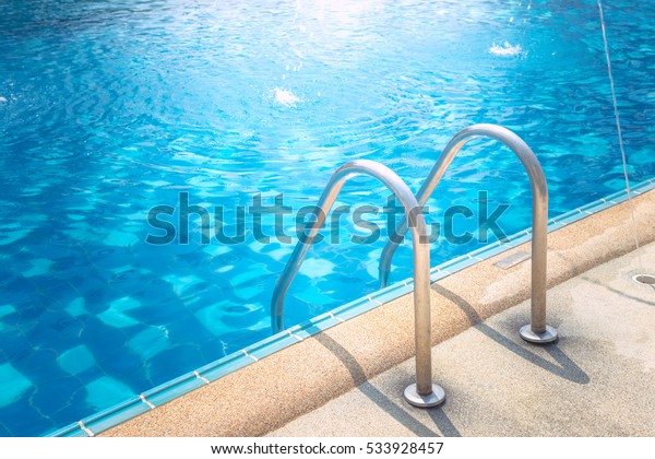 Grab bars ladder in\
the blue swimming pool