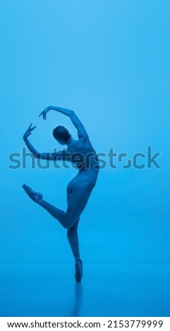 Grace. Young and graceful ballet dancer isolated on blue studio background in neon light. Art, motion, action, flexibility, inspiration concept. Contemp performance, dance
