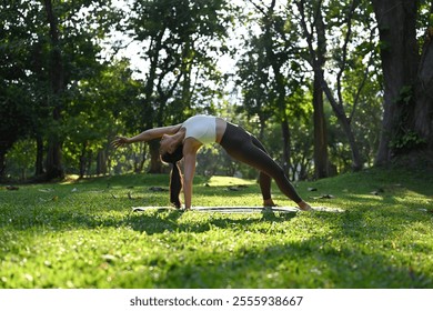 Graceful Backbend in Nature Embrace with An Asian Sporty Woman, Practices yoga outdoors. - Powered by Shutterstock