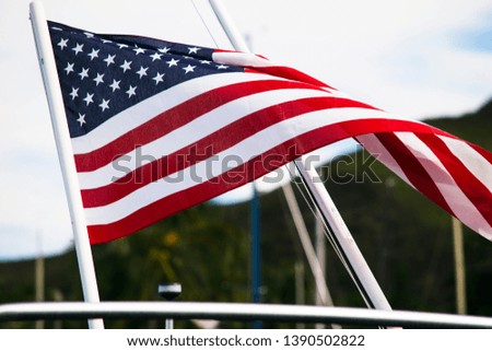 Graceful and beautiful the American flag waves in the beautiful day light from the stern of a yacht docked in the harbor