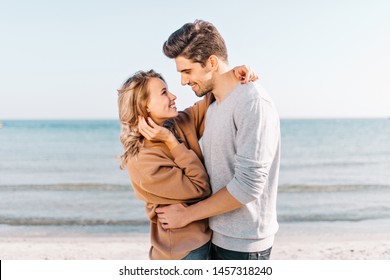 Graceful blonde girl looking at boyfriend with love on nature background. Outdoor photo of happy man dancing with wife beside sea. - Powered by Shutterstock