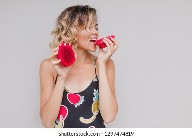 Graceful European Woman Eating Red Pitaya With Pleasure. Elegant Blonde Female Model Enjoying Tasty Dragon Fruit In Studio.