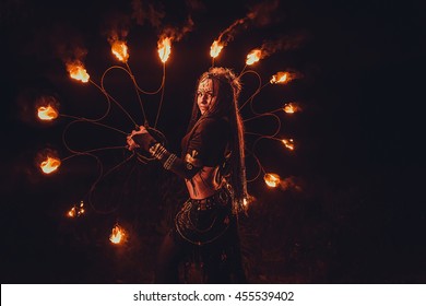 Graceful girl dancing passionate dance with fire fan in his hand. Dancer in tribal style. Fire show.