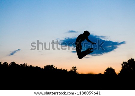 Graceful Gymnast Dancer Jumping leaps Against Stunning Sunset in a Silhouette Sky of Clouds