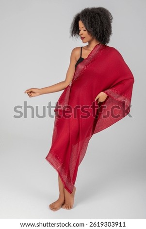 Graceful in ruby whispers, she sways barefoot, a jeweled shawl floating around her silhouette like dusk’s embers, weaving quiet power, comfort, and magnetic elegance into one serene moment tonight...
