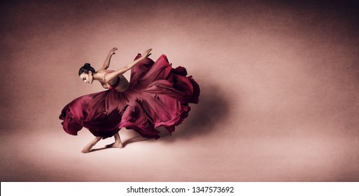 Graceful woman dancing in flowing dark red dress like rose