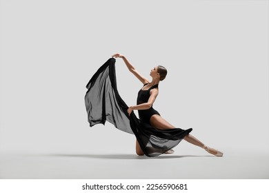 Graceful young ballerina practicing dance moves with black veil on white background - Powered by Shutterstock