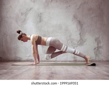 Graceful Young Brunette Woman Doing Stretching And Yoga Poses At Home Or Yoga Studio. Attractive Girl Wearing Grey Sportswear, Pants And Top Working Out Indoor.