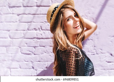 Graceful young woman with long shiny hair gladly posing while walk outside in good mood. Outdoor close-up photo of pleased girl in trendy summer hat with black ribbon enjoying sunshine. - Shutterstock ID 696809851