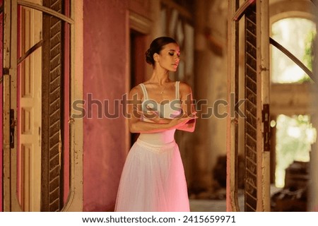 A gracious prima ballerina is dancing her choreography in rustic place. A fragile ballet dancer is performing her choreography in abandoned place. A neon light outlines her devilish side. Copy space.