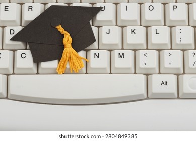 Grad cap on white computer keyboard for e-learning and remote learning