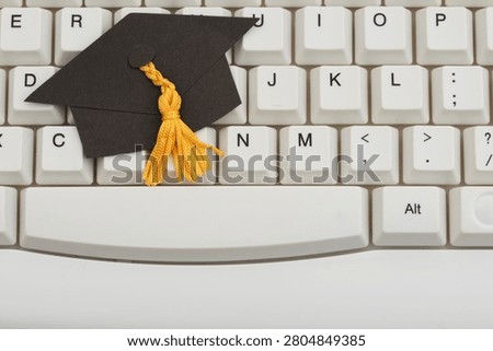 Grad cap on white computer keyboard for e-learning and remote learning