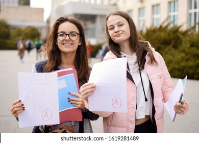 Grade / test results. Female students showing papers with perfect test result grade A, excellent mark for examination