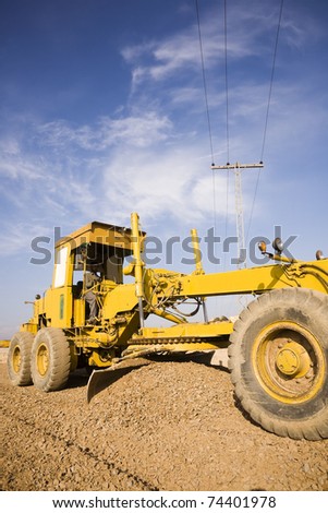 grader leveling the stone during the construction of a road.
