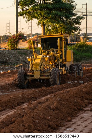 Grader is working on road construction. Grader industrial machine on construction of new roads. Heavy duty machinery working on highway. Construction equipment. Compaction of the road.