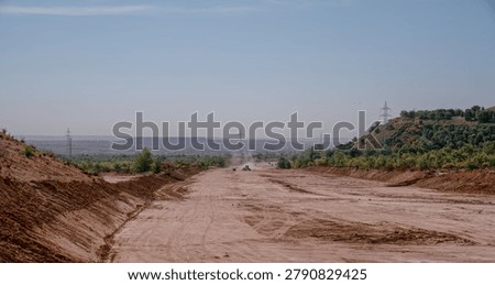 Grader working on wide undeveloped land for future road infrastructure