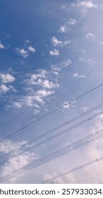 Gradient blue sky before sunset with electric cable crossed in the bottom side and white clouds in part of it