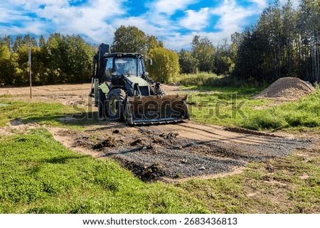Grading and leveling ground surface backhoe loader ensures uniform foundation preparation for upcoming construction projects.