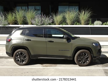 Grado, Italy. June 26, 2022. Army green Jeep Compass at the road side with some plants on behind. Side view.