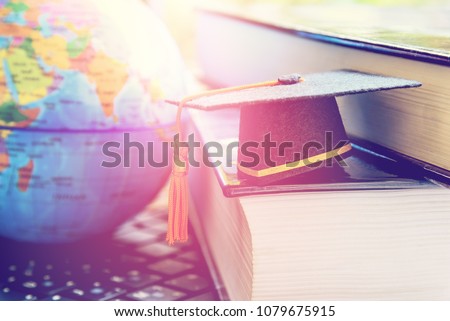 Graduate certificate program concept : Black graduation cap on two big text books and a laptop, depicts try or attempt for students or learners to achieve the goal or gain success in higher education.