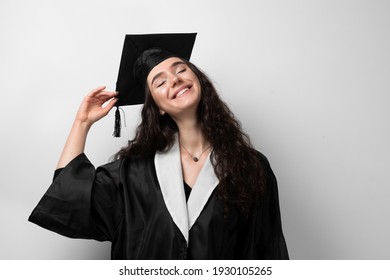 Graduate Girl With Master Degree In Black Graduation Robe And Cap On White Background. Happy Young Woman Careerist Have Success In Her Business.