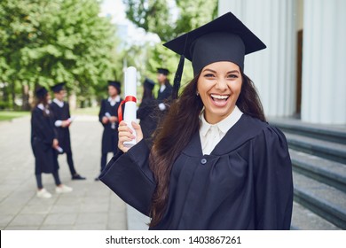 Graduate Girl Smiling Against The Background Of A Group Of Graduates.