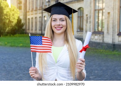 Graduate Student With US Flag And Diploma. Graduation Day On The Campus Of The University.