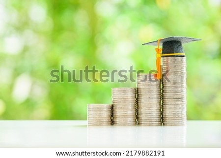 Graduate study abroad, education concept : Graduation cap sits atop stacks of coins, depicting bursaries and scholarships that provide financial assistance to students with no obligation to repay.
