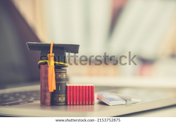 Graduate study abroad program to broaden learner\'s\
world view, e-learning concept Graduation cap, foreign books on a\
laptop, depicts student attemptong to study from a distance or\
learning from home.