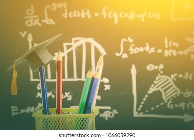 Graduate Study Abroad Program Concept : Graduation Cap On A Blue Pencil In A Green Metal Box Near A Chalk Board With Math / Calculus Formula Or Arithmetic Operation / Equation, Bar Graph Or Charts.