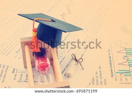 Graduate study abroad program concept : Graduation cap / hat on hour glass and a scroll of certificate nearby. Graduate study abroad program is a program that accept students from foreign countries.
