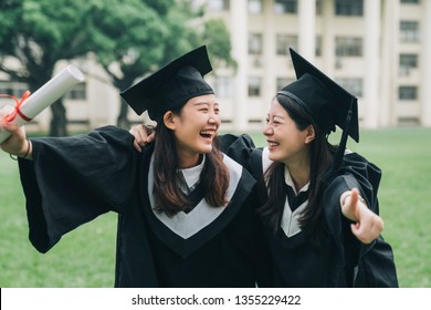 Graduation Asian Female Friends Hold Diploma. Cheerful Ladies Students Hugging Shoulders Arms With Thumb Up Finger Hand Gesture Best Sign. Beautiful Cheerful Women Students Looking Each Other Smiling