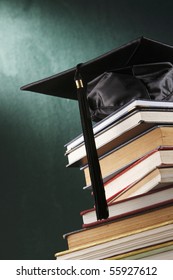 Graduation Cap With Book  In Front Of Black Board