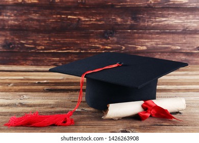 Graduation Cap With Diploma On Brown Wooden Table