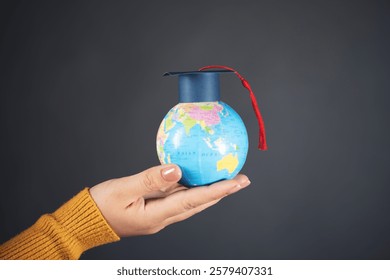 Graduation cap on globe model in woman hand