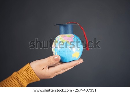 Graduation cap on globe model in woman hand