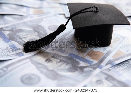 Graduation cap on top of a pile of US hundred dollar bills. Education financing, student loan concept.