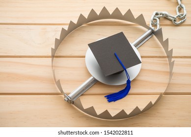 Graduation Cap In A Trap On Wooden Table Background. College Or University Degrees Are Not Important In Future, Education Loan And Unemployment Or Jobless Rate Problem Concept. 