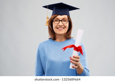 Graduation, Education And Old People Concept - Happy Senior Graduate Student Woman In Mortar Board With Diploma Laughing Over Grey Background