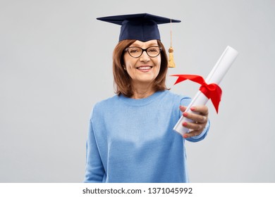 Graduation, Education And Old People Concept - Happy Senior Graduate Student Woman In Mortar Board With Diploma Laughing Over Grey Background