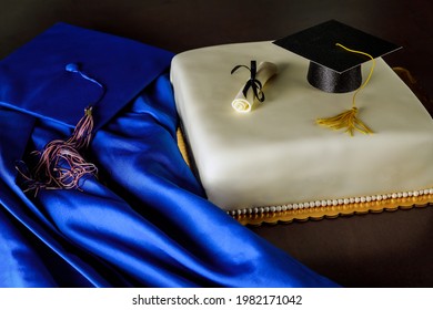 Graduation Fondant Cake With Blue Hat And Gown On Dark Background.