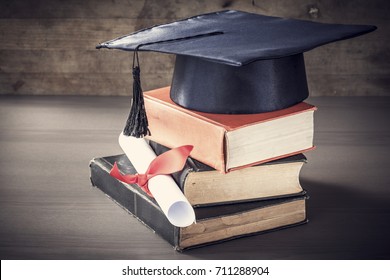 Graduation Hat And Diploma With Book On Table