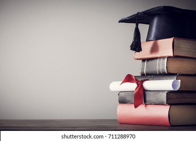 Graduation Hat And Diploma With Book On Table